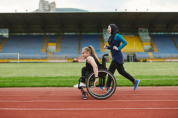 Image showing A Muslim woman in a burqa running together with a woman in a wheelchair on the marathon course, preparing for future competitions.