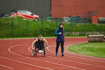 Image showing A Muslim woman in a burqa running together with a woman in a wheelchair on the marathon course, preparing for future competitions.