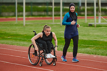 Image showing A Muslim woman in a burqa running together with a woman in a wheelchair on the marathon course, preparing for future competitions.