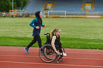 Image showing A Muslim woman in a burqa running together with a woman in a wheelchair on the marathon course, preparing for future competitions.