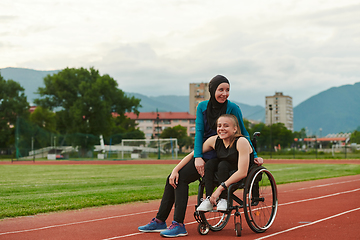 Image showing A Muslim woman wearing a burqa resting with a woman with disability after a hard training session on the marathon course