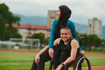 Image showing A Muslim woman wearing a burqa resting with a woman with disability after a hard training session on the marathon course