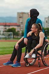 Image showing A Muslim woman wearing a burqa resting with a woman with disability after a hard training session on the marathon course