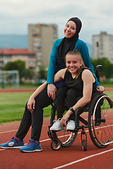 Image showing A Muslim woman wearing a burqa resting with a woman with disability after a hard training session on the marathon course