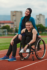 Image showing A Muslim woman wearing a burqa resting with a woman with disability after a hard training session on the marathon course