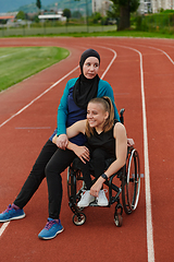 Image showing A Muslim woman wearing a burqa resting with a woman with disability after a hard training session on the marathon course