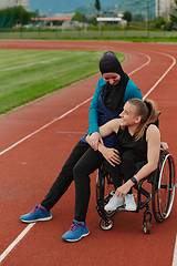 Image showing A Muslim woman wearing a burqa resting with a woman with disability after a hard training session on the marathon course