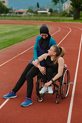 Image showing A Muslim woman wearing a burqa resting with a woman with disability after a hard training session on the marathon course