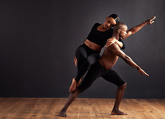 Image showing Balance of male and female energies. A female and male contemporary dancer performing a dramatic pose in front of a dark background.