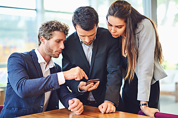 Image showing Lets enjoy connectivity together. Cropped shot of businesspeople using a cellphone together indoors.