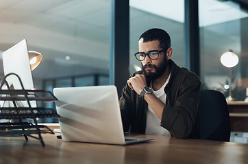 Image showing The more you focus the quicker youll find the solution. Shot of a young businessman using a laptop during a late night in a modern office.