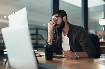 Image showing How many more nights of this can I take. Shot of a young businessman feeling stressed while working late at night in a modern office.