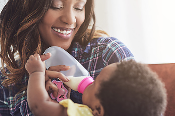 Image showing Somebodys hungry. Cropped shot of a young mother feeding her baby girl at home.