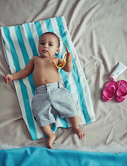 Image showing Excuse me while I get my beach on. Concept shot of an adorable baby boy lying on a towel at a make believe beach.