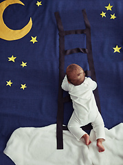 Image showing Dream chaser. Concept shot of an adorable baby boy climbing a ladder against an imaginary night time background.