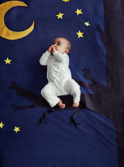 Image showing Rock a bye baby on the treetop. Concept shot of an adorable baby boy sitting on a tree against an imaginary night time background.