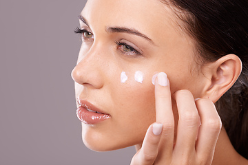 Image showing Giving her skin the hydration it needs. Studio shot of a beautiful young woman applying a skincare product to her face.