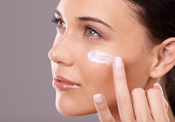 Image showing Showing her skin some love. Studio shot of a beautiful young woman applying a skincare product to her face.