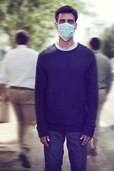 Image showing Flu season is here. Shot of a man wearing a surgical mask in a crowd.