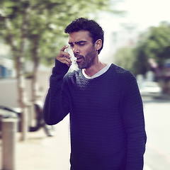 Image showing Seeking relief from his wheezing chest. Cropped shot of a young man using his asthma pump outside.