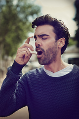 Image showing Getting his symptoms under control. Cropped shot of a young man using his asthma pump outside.