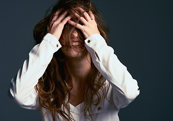 Image showing Messy hair dont care. Studio shot of an unrecognizable woman covering her face with her hair against a blue background.