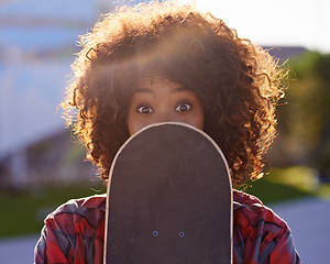 Image showing A little fun in the skate park. A young woman with a quirky expression holding her skateboard.