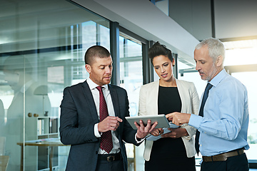 Image showing Using technology to boost their brainstorming sessions. Shot of a business team using a digital tablet while having an informal meeting.