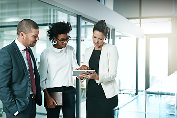 Image showing I think we should go with this idea. Shot of a business team using a digital tablet while having an informal meeting.