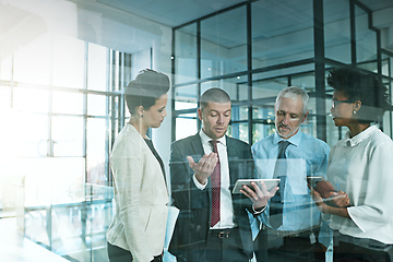 Image showing I just need some advice to help me to decide.... Shot of a business team using a digital tablet while having an informal meeting.