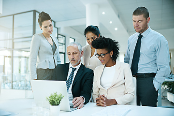 Image showing Trying to convince his team to agree with him.... Shot of a group of businesspeople coming together to work on something on a laptop.