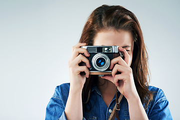 Image showing Retro is the way to go. Studio portrait of a young woman using a vintage camera against a grey background.