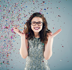 Image showing Toss some confetti in the air and celebrate. Studio shot of a young woman with confetti falling around her against a grey background.