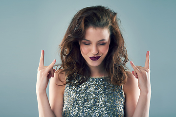 Image showing I rock my own style. Studio shot of a young woman making a hand gesture against a grey background.