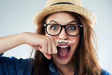 Image showing Dont take life too seriously. Studio portrait of a young woman holding her finger under her nose with a moustache drawn on it.