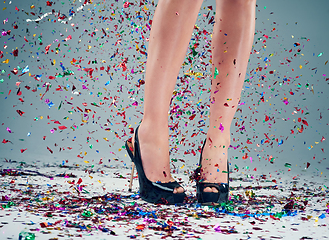 Image showing Are you ready to party. Studio shot of a young womans legs in a pair of heels with confetti falling around against a grey background.