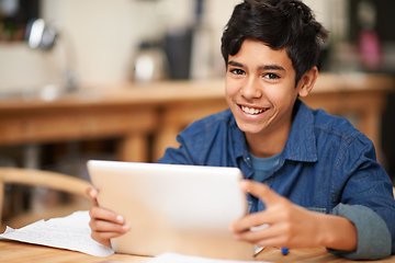 Image showing Growing through online education. Portrait of a young teenage boy using a digital tablet while doing his homework.