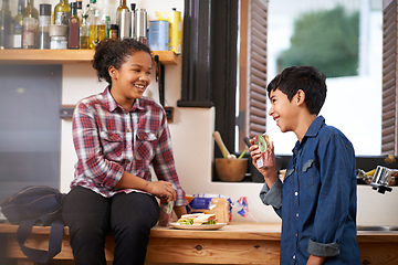 Image showing Having a tasty nibble after school. Shot of two young teenagers enjoying a snack together in the kitchen.