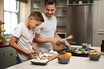 Image showing Youre such a natural. Cropped shot of a young boy helping his father cook in the kitchen.