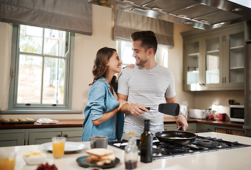 Image showing Are you trying to score some brownie points. Shot of a young woman embracing her partner while he cooks breakfast.