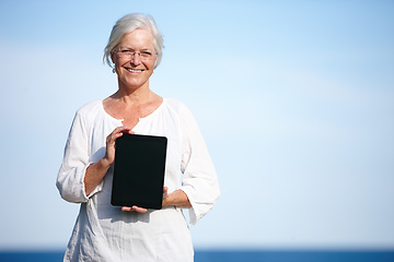 Image showing Shes found some great relaxation exercises online. Portrait of a mature woman holding up a digital tablet while standing outside.