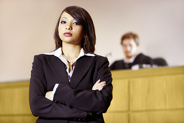 Image showing Well-qualified to win in court. Stern young advocate standing in the courtroom with her arms folded.