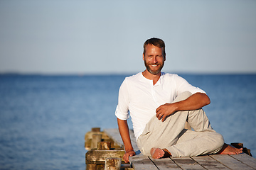 Image showing Stretching his muscles to stay flexible. Portrait of a handsome mature man doing yoga on a pier out on the ocean.