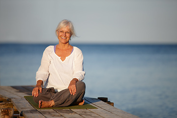 Image showing The best yoga spot. Portrait of an attractive mature woman doing yoga on a pier out on the ocean.