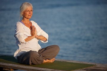 Image showing Tranquility by the ocean. Shot of an attractive mature woman doing yoga on a pier out on the ocean.