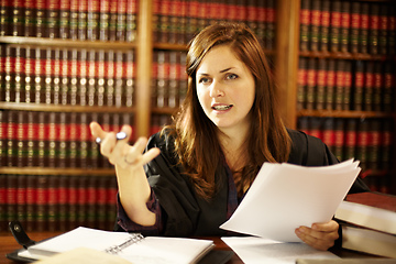 Image showing Setting a legal precedence. Attractive young judge sitting at her desk discussing the law.