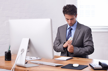 Image showing Pocketing some cash. A young businessman putting cash in his pocket.