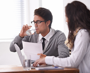 Image showing This interview is giving me a dry mouth. A young man drinking water during an interview.