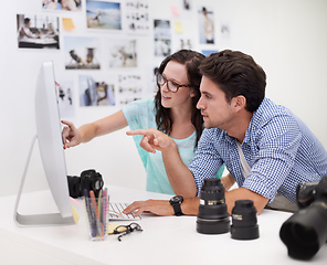 Image showing Deciding on the perfect image.... Two young photographers looking at photos on a digital camera in their studio.