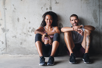 Image showing Were down but not out. Portrait of a sporty young couple sitting down against a wall while exercising inside a parking lot.